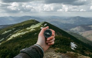 Hand holding compass overlooking mountains