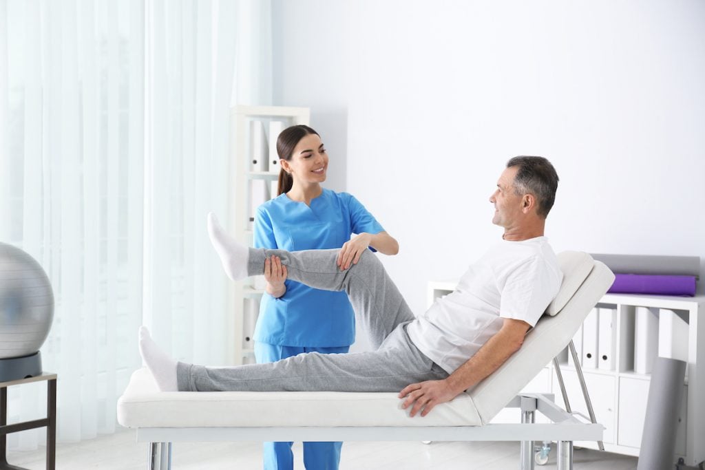 Female physiotherapist doing exercises with a patient after hip replacement surgery.