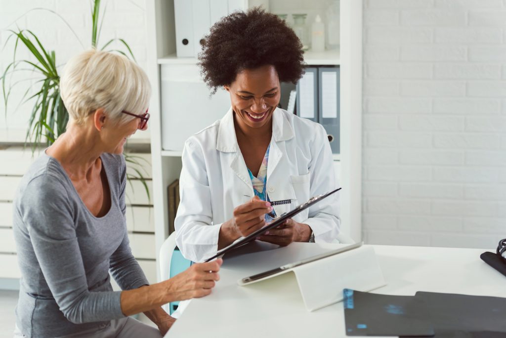 A female surgeon consulting with an elderly female patient about hip replacement surgery.