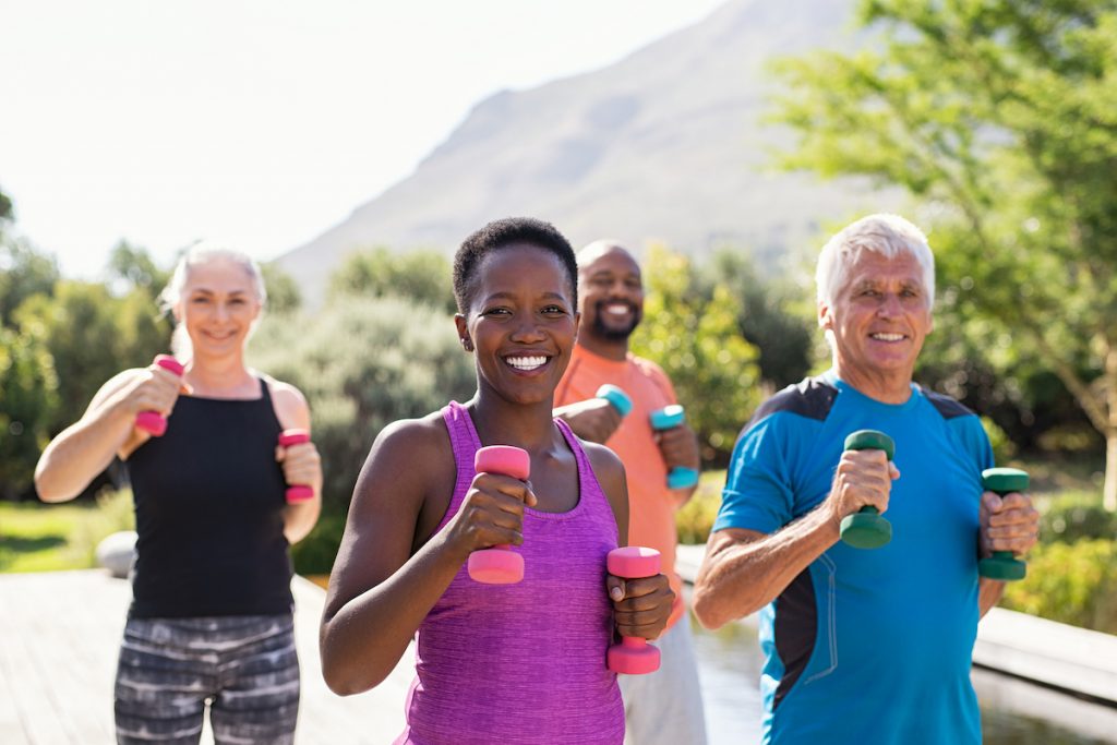 A group of mature people, both genders, exercising outdoors.