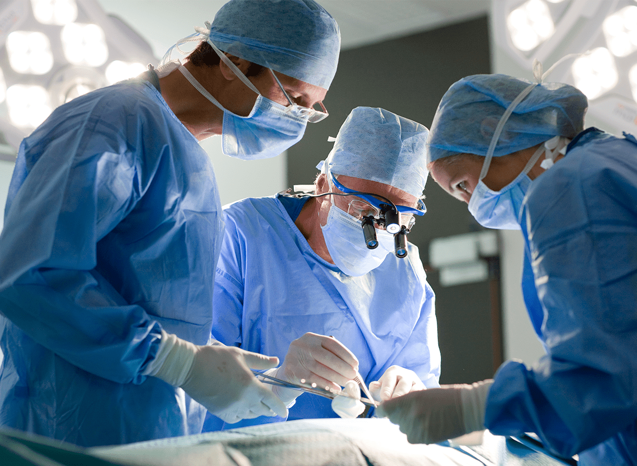 Three surgeons gathered around a table performing an operation