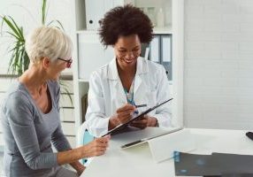 A female surgeon consulting with an elderly female patient about hip replacement surgery.