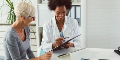 A female surgeon consulting with an elderly female patient about hip replacement surgery.